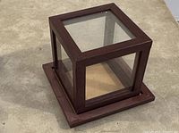Glass display case with five glass sides and removable top, dark brown wood base and trim.