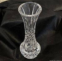 Clear 7-inch crystal glass vase with intricate cut design on a black fabric background.