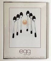 Framed poster titled 'Egg' showing spoons arranged around an egg yolk on white background, with artist and graphics credit text.