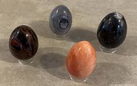 Top-down angled photo showing all four mineral eggs on clear stands, highlighting varied colors and patterns of each egg