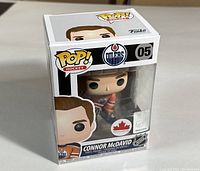 Straight-on angled photo of unopened boxed Funko Pop vinyl figure Connor McDavid wearing Edmonton Oilers orange jersey #05, showing box front and side with logos and figure visible.