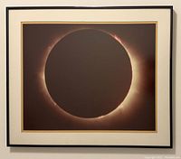 Image of framed photograph showing a total solar eclipse with double cream and gold matting in a sleek dark frame.