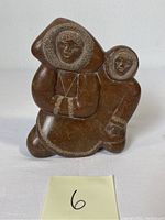 Front view of the soapstone sculpture showing two Eskimo figures with detailed etched facial features and parka hoods.