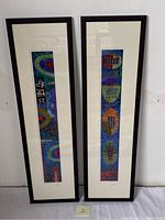 Frontal view of the set of two framed embroidered textile art pieces featuring colorful abstract geometric embroidery in black frames.