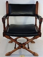 Front view of the vintage cross-legged armchair showing wooden frame and black leather upholstery.