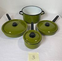 Full set of four vintage green enamel cookware pieces including two frying pans (one with lid, one without), a large stockpot with handles, and a small saucepan with lid.