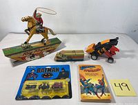 Full view of all vintage toys including Roy Rogers tin toy, Batman mini trains, Superman and Spiderman comic book, plastic van, and Tonka race car on flat surface.