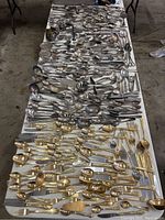 Full overhead view of all the servingware items on a table, showing a clear division between gold plated and silver plated utensils.