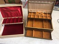 Two vintage jewelry boxes side by side, showing their interiors and compartment layouts.