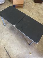 Top angled view of the table showing two black rectangular tabletops and metal legs.