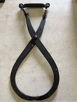 Amish black iron ice tongs with leather handle resting on a light surface.