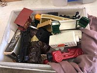 Overview of bin with multiple Avon car and train shaped cologne and perfume bottles in various colors and styles.
