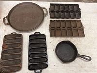 Overview of all seven cast iron items showing two pans and five specialty baking molds.