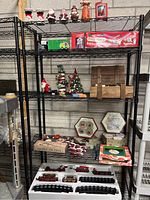 Full lot on three-tier black shelf including Christmas train set, figurines, plates, dishes, and ornaments.