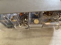 Close-up view of several drawers showing charms, clasps, and other metal jewelry findings