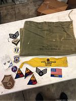Overview of all patches, armband, and field bag laid on a white surface