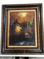 Full view of the framed vintage oil painting showing a historic architectural scene at night with warm lighting and rich colors.