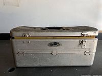 Closed vintage gray Sears metal tackle box showing dents and clasp closure issues.