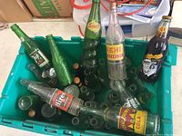 Overview of vintage soda bottles featuring 7UP, Squirt, Firestone, Royal Crown Cola, Nehi, and Orange Crush bottles in plastic container.
