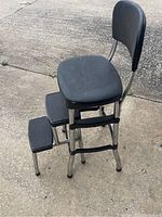 Side view showing black vinyl cushioned seat, backrest and chrome frame, two ribbed step platforms for stepping up