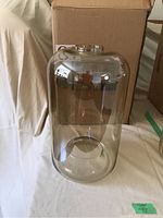 Full view of the clear glass cylindrical lampshade on a cloth surface showing size and shape.