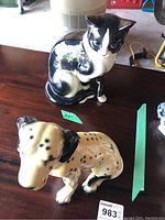 Both dog and cat figurines shown from a top side angle on a wood surface