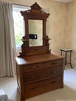 Full view of antique wooden dresser with three drawers beneath a large removable mirror featuring carved wood details.