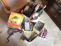 Full view of the lot showing the Armoral orbital polisher box, two work lamps, hand saw, electric cords, several tubes of Kwik Seal, and a box of screws.