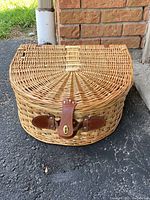 Closed wicker picnic basket showing front leather strap and clasp