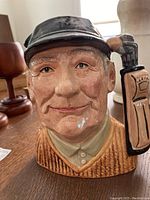 Front view of Royal Doulton golfer character jug showing detailed facial features and golf bag handle.