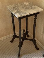 Full view of the wood side table with a white marble top and ornate turned legs.