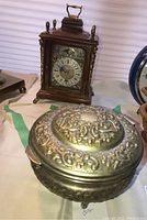 Clock and metal lidded dish shown together, highlighting overall shape and details of both items