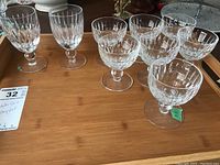Nine crystal stemware glasses on a wooden rectangular tray, showing front and top views of glasses with etched patterns