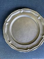 View of stacked pewter platters showing scalloped edges and natural patina.