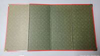Four-panel folding frame from the back showing green textured paper backing with gold corner protectors and red borders.