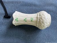 Side view of the cream-colored Belleek vase with shamrock decoration and basket weave base detail.