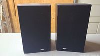 Pair of B&W 201i bookshelf speakers with fabric grills on, black wood grain finish, front and side views.