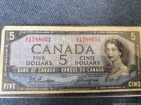 Front side of 1954 Canadian $5 banknote showing Queen Elizabeth II portrait and serial number 21788051 twice in red ink.