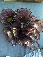 Group of 11 amethyst purple glass punch cups showing their twisted swirl design and handles designed to hook onto bowls.