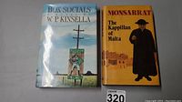 Photo showing both hardcover books together. "Box Socials" by W.P. Kinsella has a scenic sports-themed cover and "The Kappillan of Malta" by Nicholas Monsarrat has a yellow cover with a cleric figure.