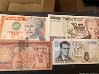 Four foreign banknotes from Peru, Turkey, Saudi Arabia and Belgium placed on a brown surface.