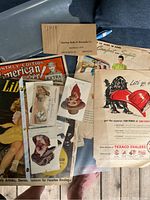 Top view of assorted vintage paper items showing the American Messenger 1946 magazine, postcards, and advertisements including the Texaco ad with a dog pouring gasoline.