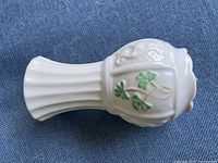 Side view showing white porcelain fluted neck and shamrock decoration on the curved body of the vase
