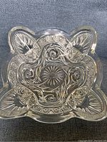 Top-down view of the square Victorian pressed glass bowl showing the intricate starburst, swirl, and floral design patterns in relief across the bottom of the bowl.