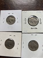 Top side of four Buffalo nickels in white cardboard coin holders, two displaying the date 1936.