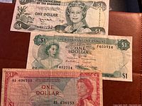 Photo showing three vintage one dollar banknotes: two from The Bahamas and one from East Caribbean Currency Authority.