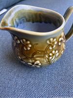 Front view of the Wade Ireland creamer showing the spout, handle, and floral relief pattern with glazed finish.