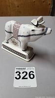 Side profile of the white bone china reindeer figurine with blue, black, and red painted details on a rectangular base.