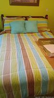 Bed with wooden spindled headboard, comforter, and pillows laid out on bed from front view