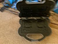 Black device possibly a remote dog trainer placed on carpet.